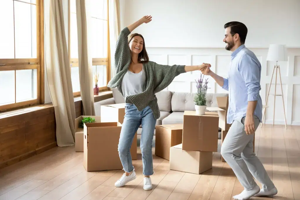 Une femme et un homme très heureux d'emménager dans leur nouvelle maison avec leurs cartons